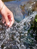 VRK Transparenz – Eine Hand greift in einen Bach mit klarem Wasser.