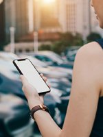 VRK eVB-Nummer – Eine junge Frau steht mit Ihrem Handy vor neuen Autos.